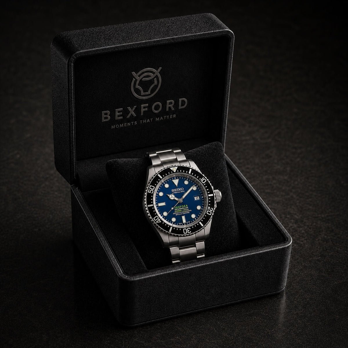 A Bexford wristwatch with a blue dial and silver stainless steel case, displayed inside an open black Bexford presentation box on a dark background.